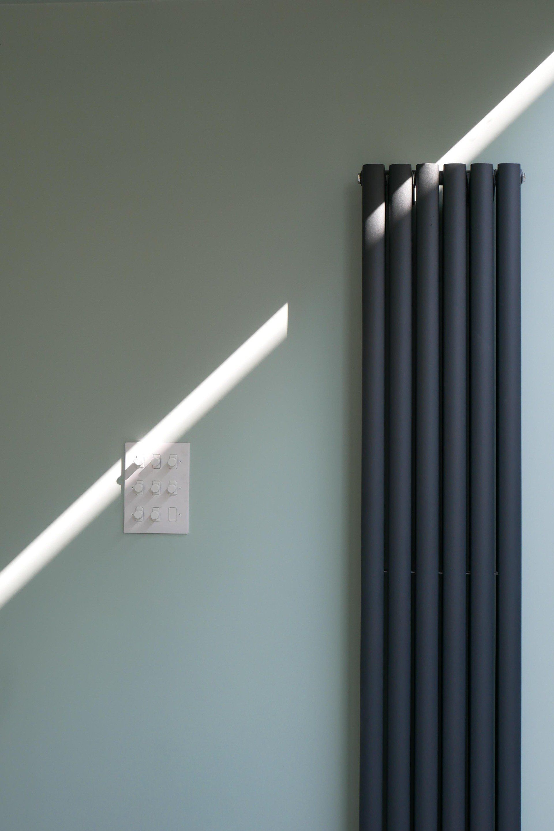 Mint-green wall with diagonal sunlight, a small square clock, and gray curtains on the right