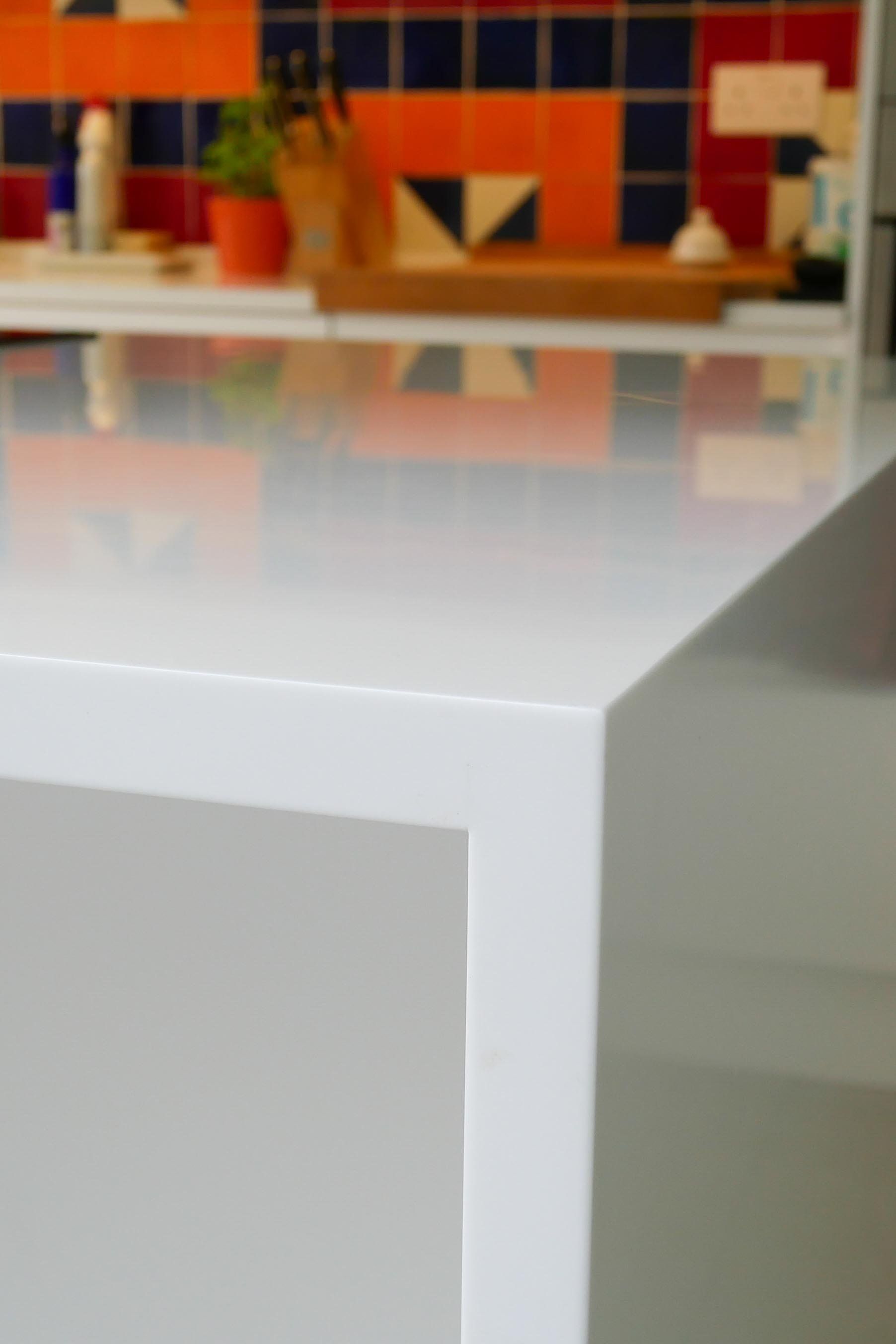 White table in front of a blurred colorful mosaic wall and shelf area