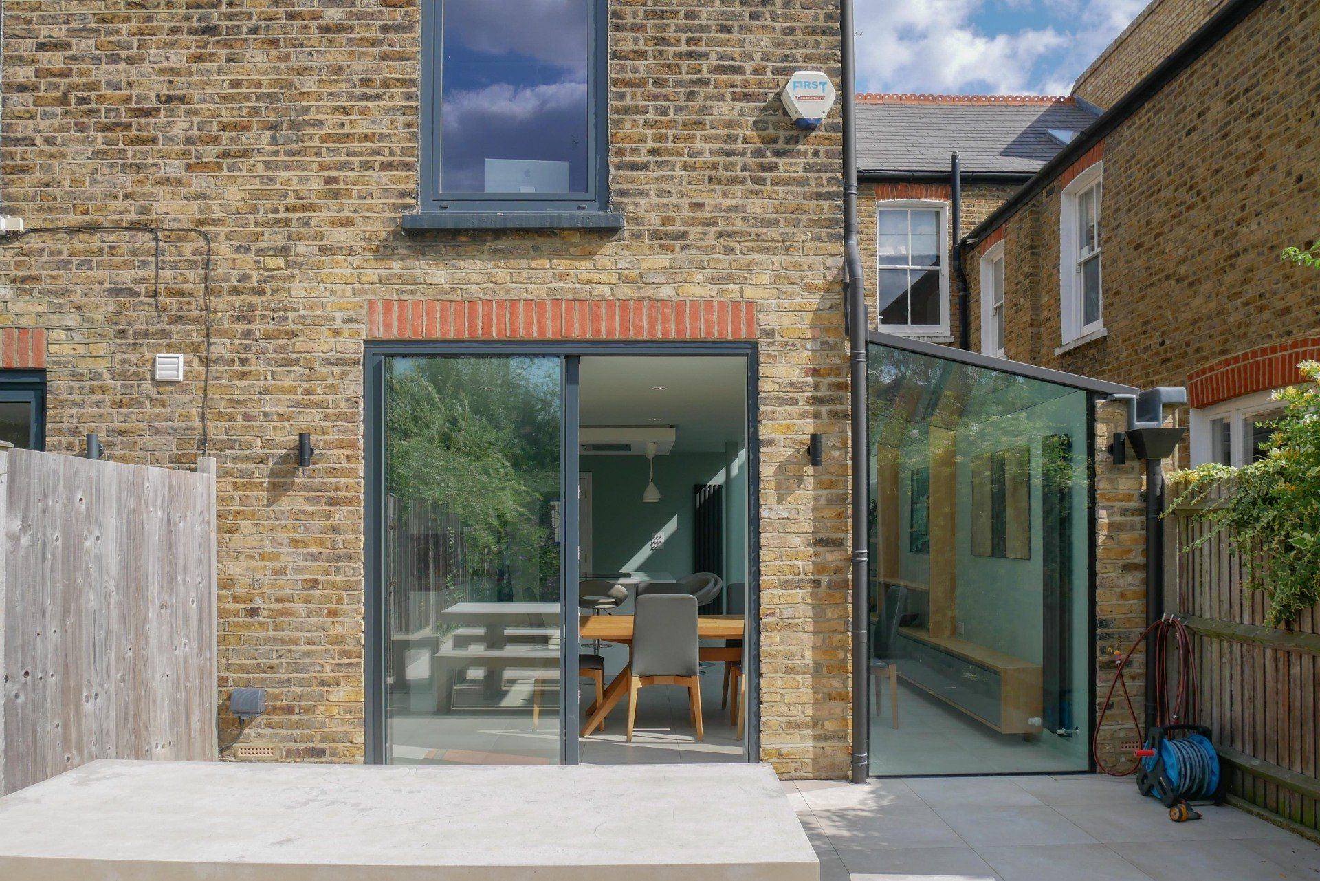 Brick house patio with large sliding glass doors and a narrow glass side extension