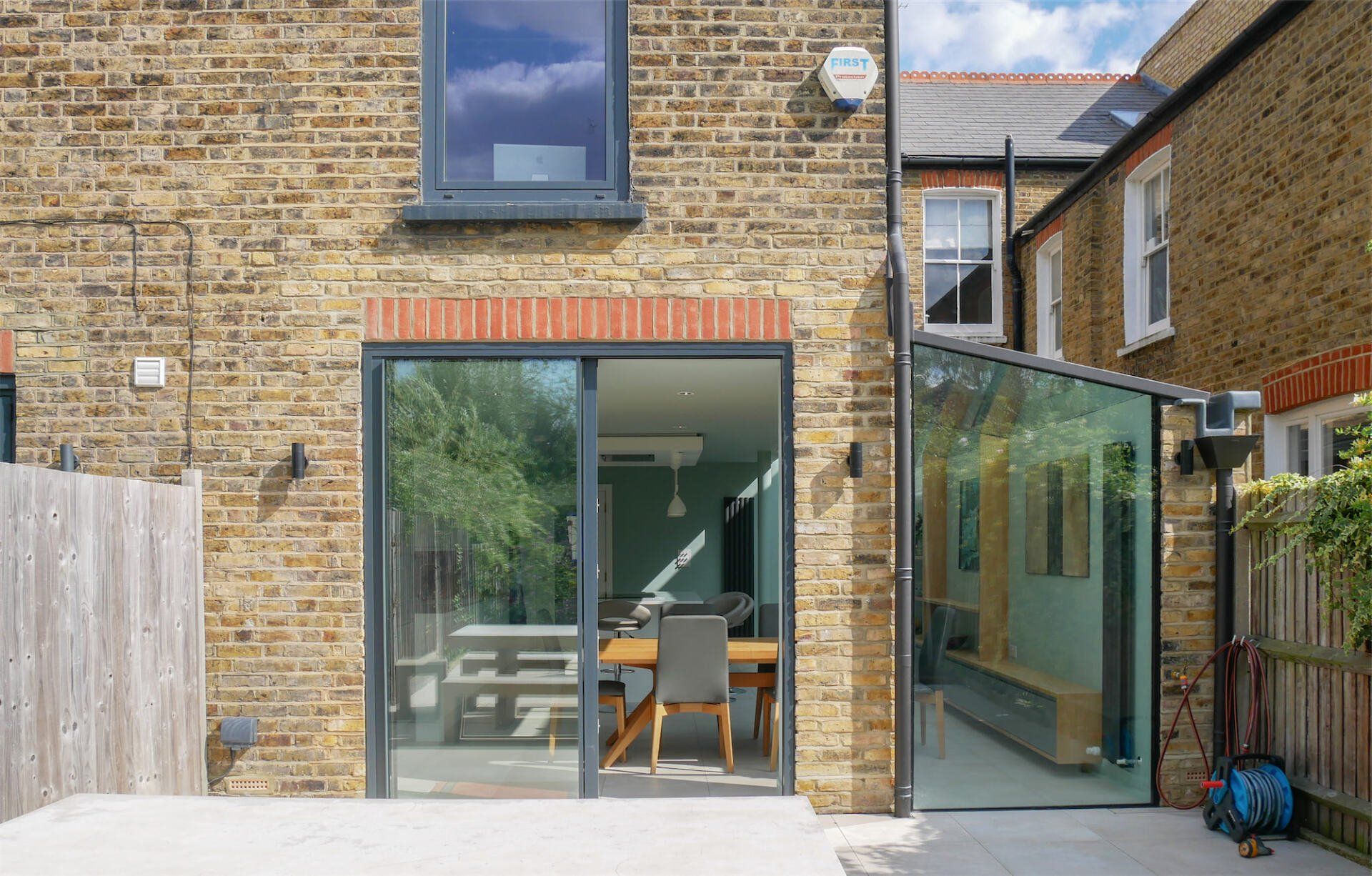 Back of brick house with glass doors opening to a patio and modern kitchen dining area