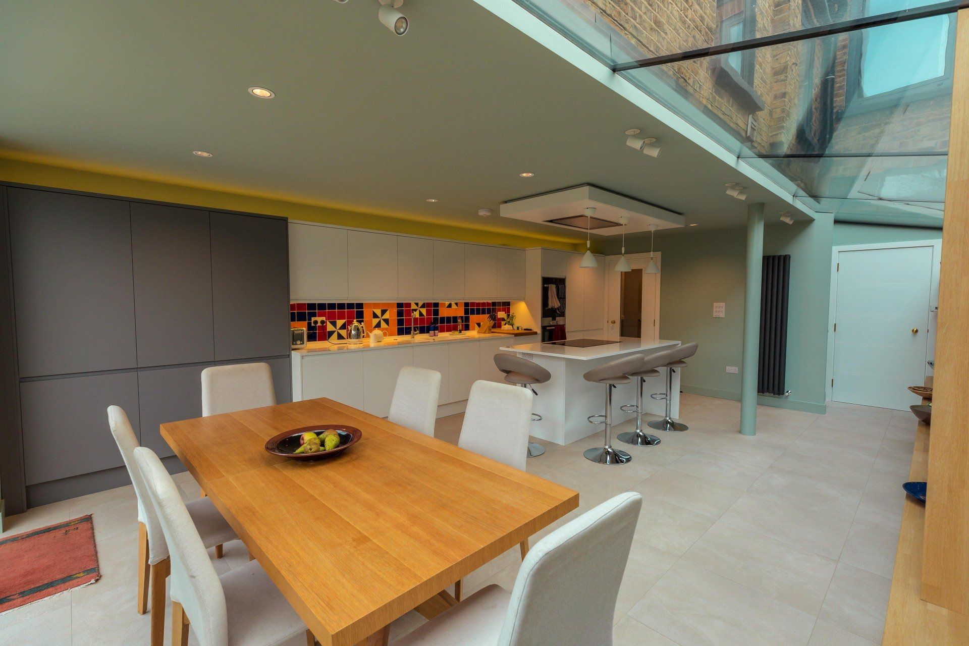Modern open-plan kitchen and dining area with wood table, white chairs, and long island counter