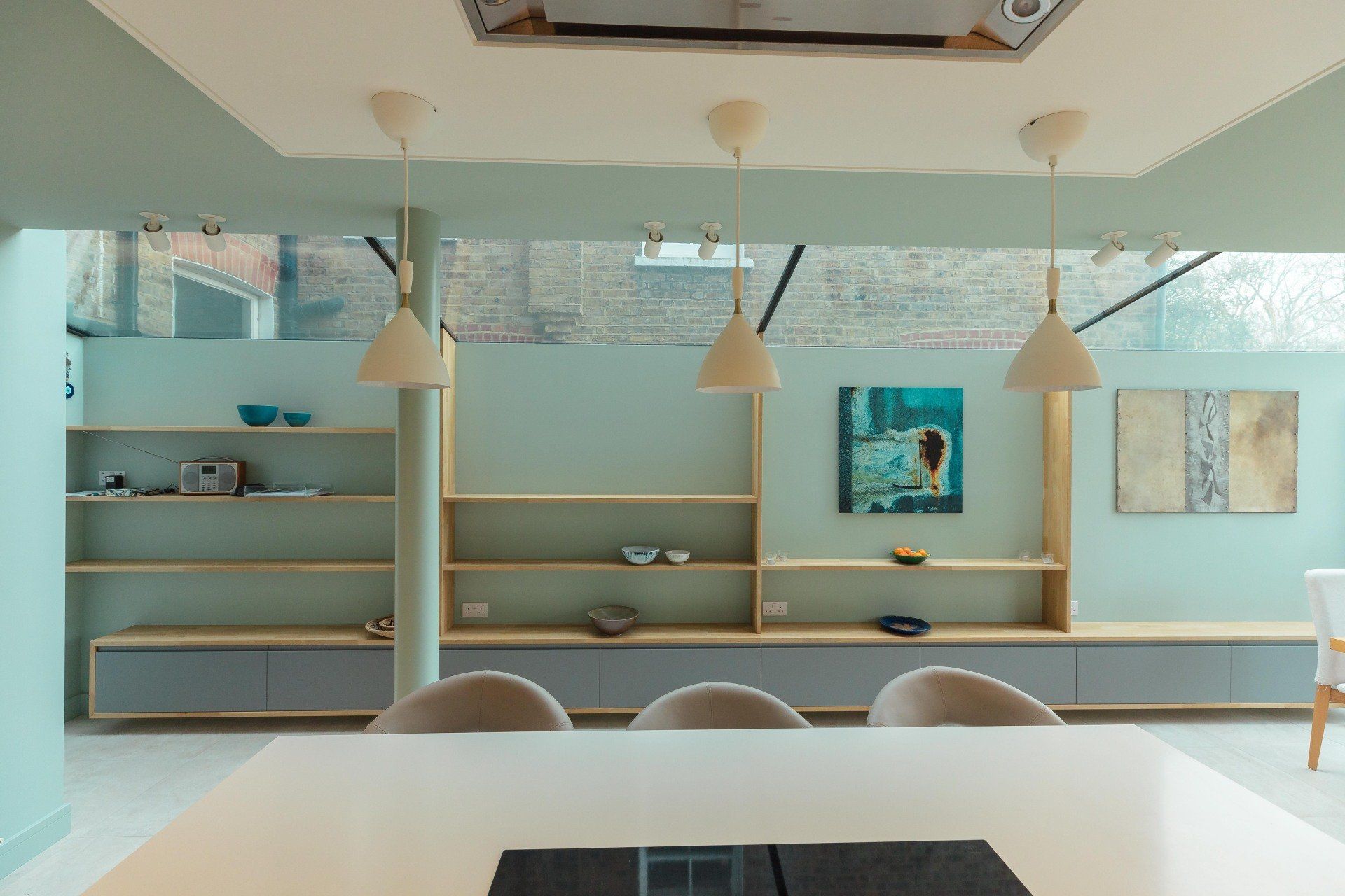 Modern pastel café interior with wooden shelves, hanging lights, and a white table in the foreground