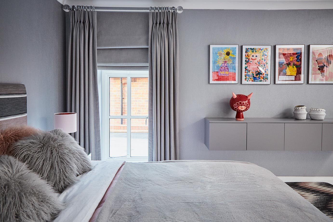 Modern gray bedroom with bed, window with curtains, and wall art above a dresser