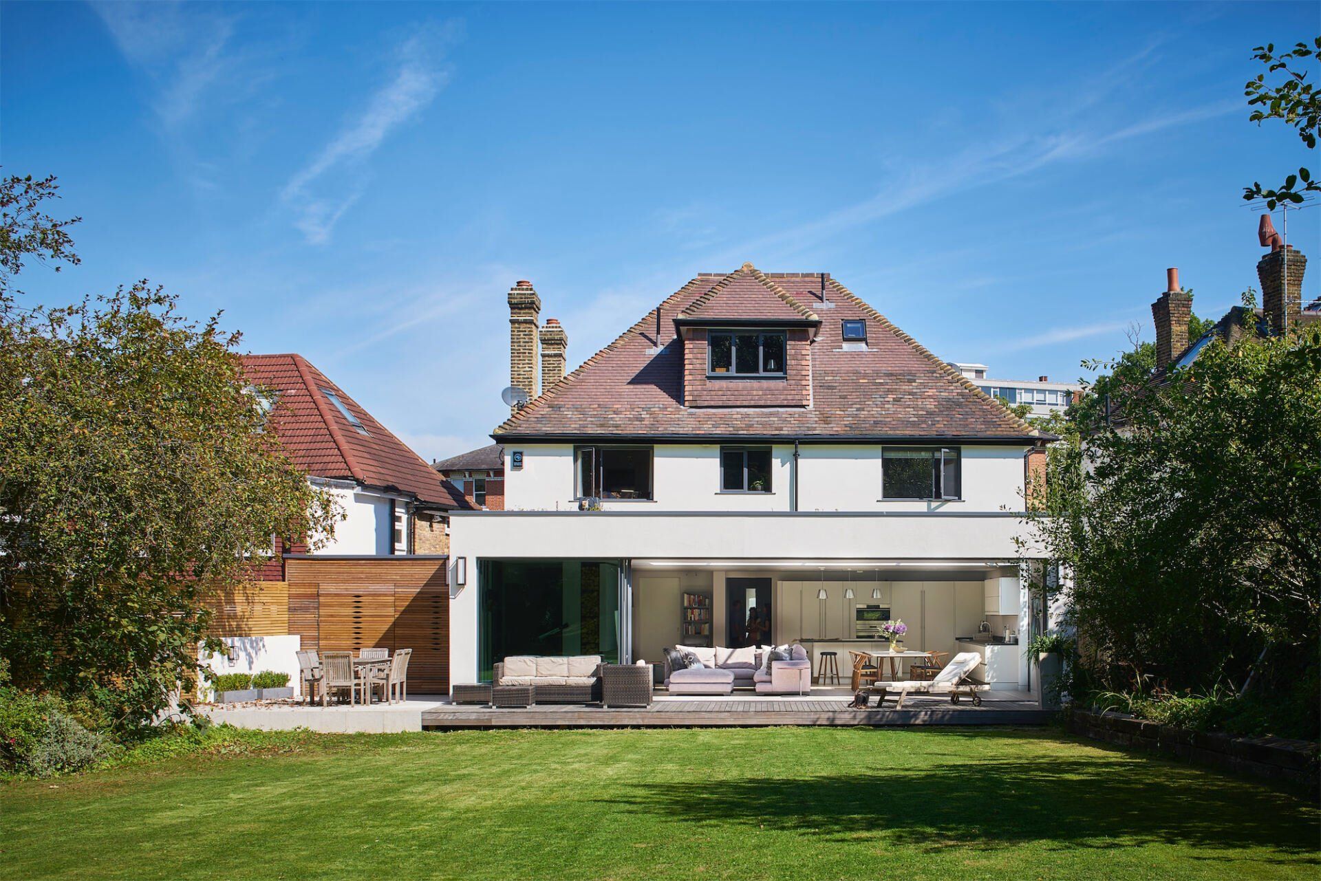 Back view of a house with a patio and green lawn under a blue sky