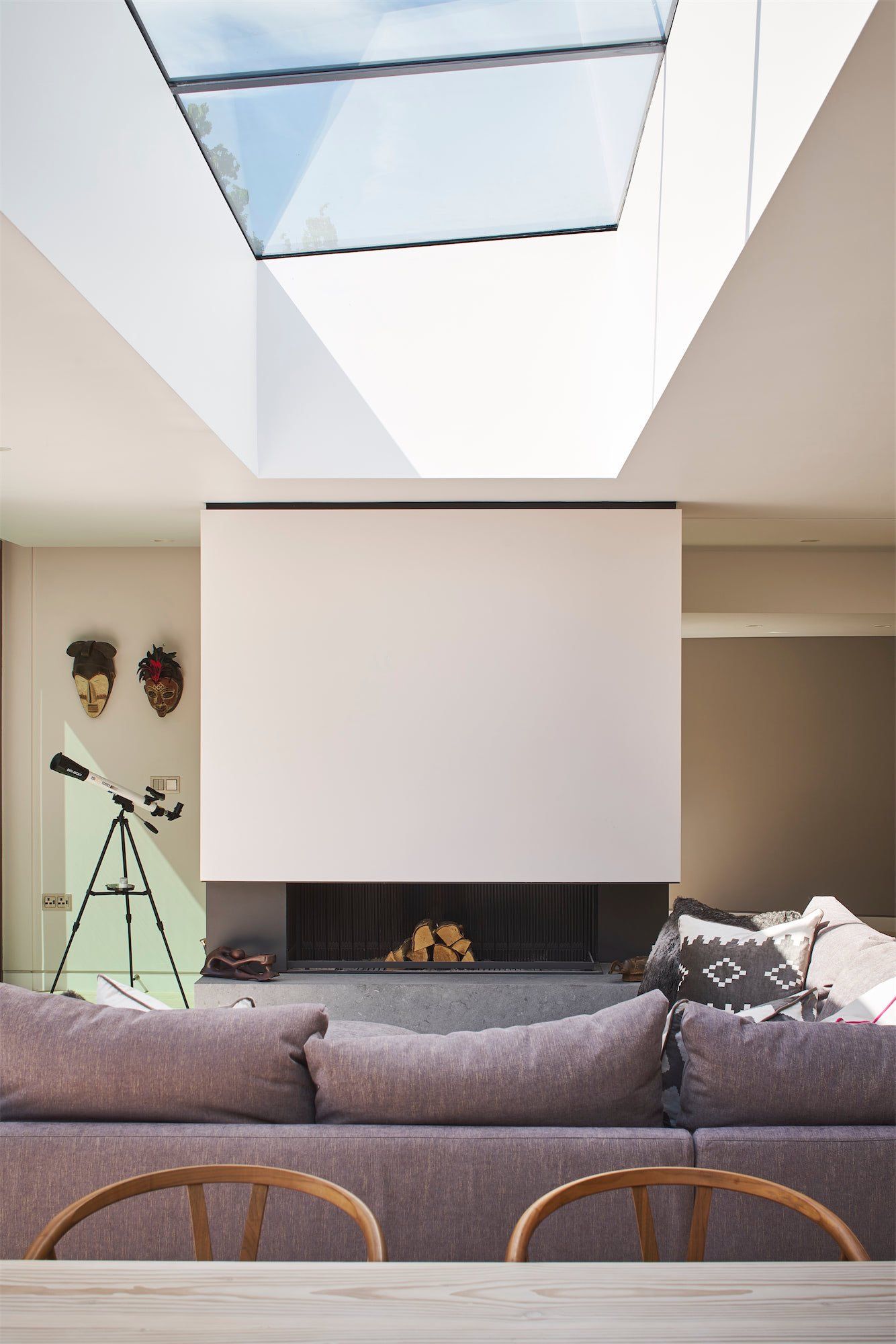 Modern living room with skylight, white projection screen, gray sofa, and fireplace