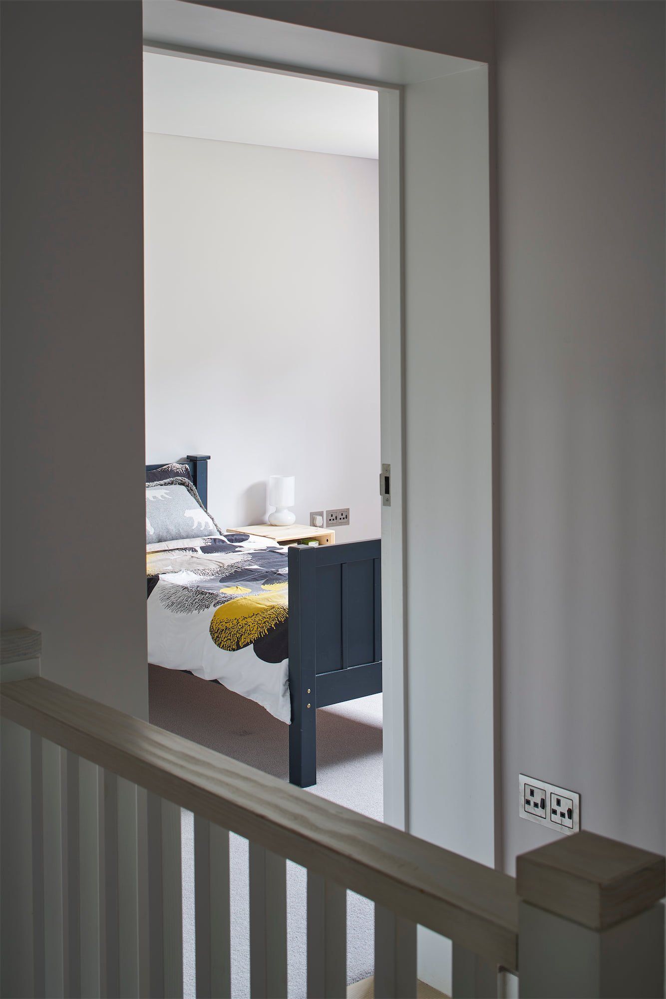 Stair landing with a doorway into a bedroom with a bed, chair, and yellow blanket.