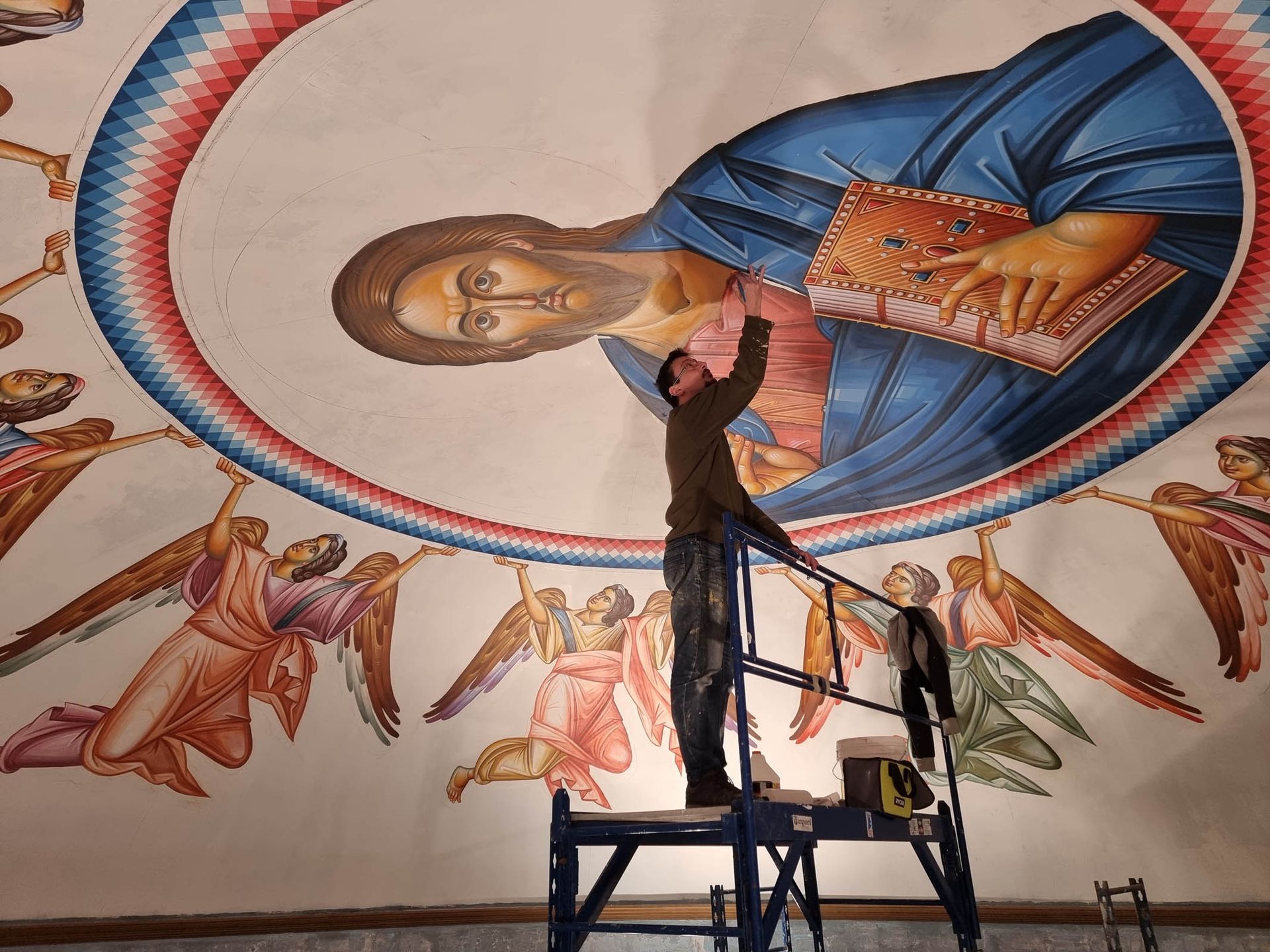 Artisan installing Christ Pantocrator dome icon with angels in Byzantine church.