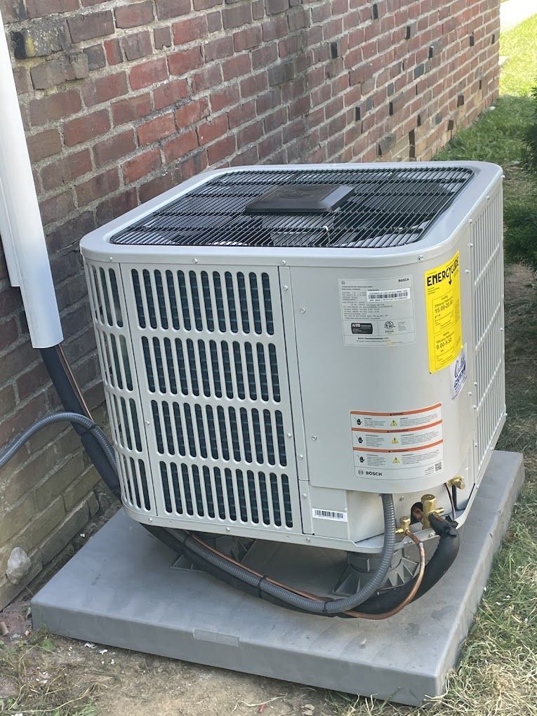 An air conditioner is sitting on top of a concrete platform next to a brick wall.