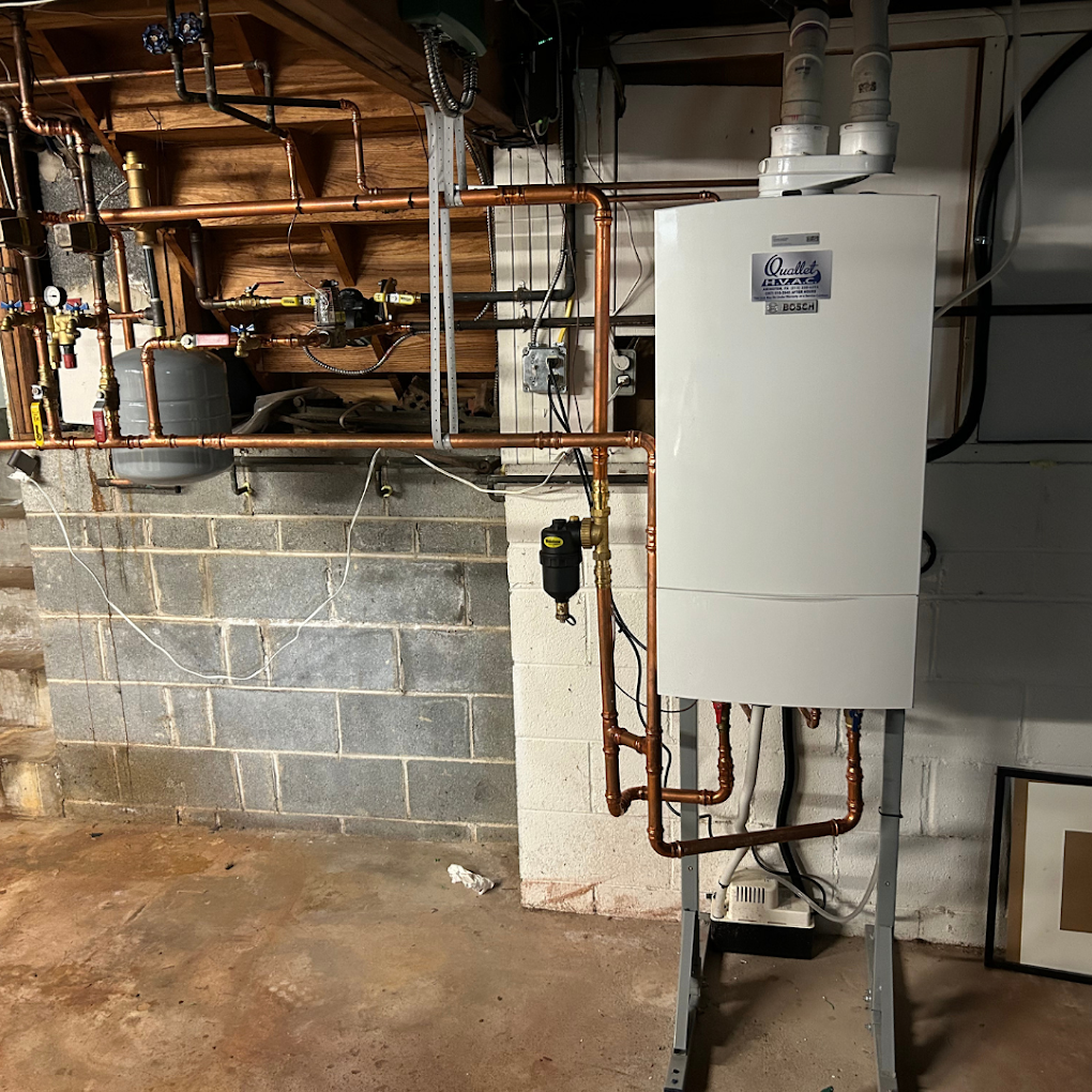 A boiler is sitting in a basement next to a brick wall