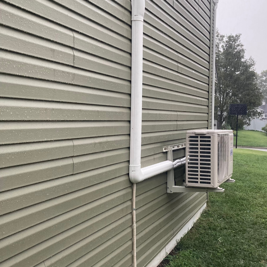 A white pipe is attached to the side of a house.