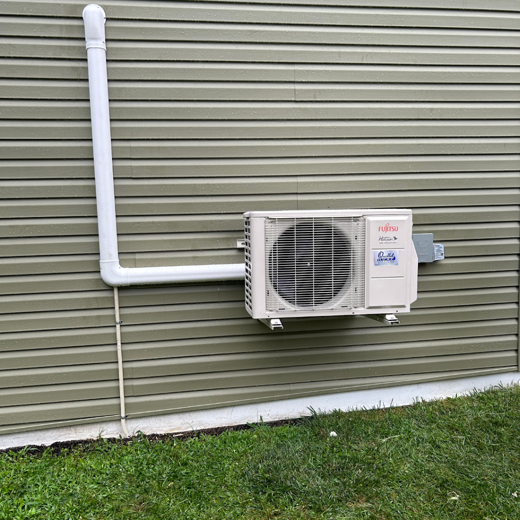 A white air conditioner is mounted on the side of a house.