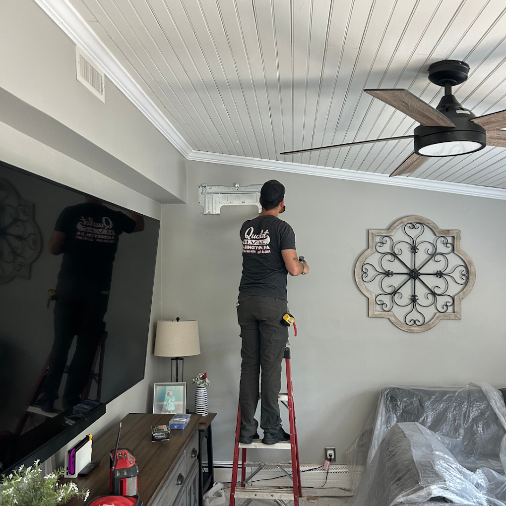 A man is standing on a ladder in a living room.