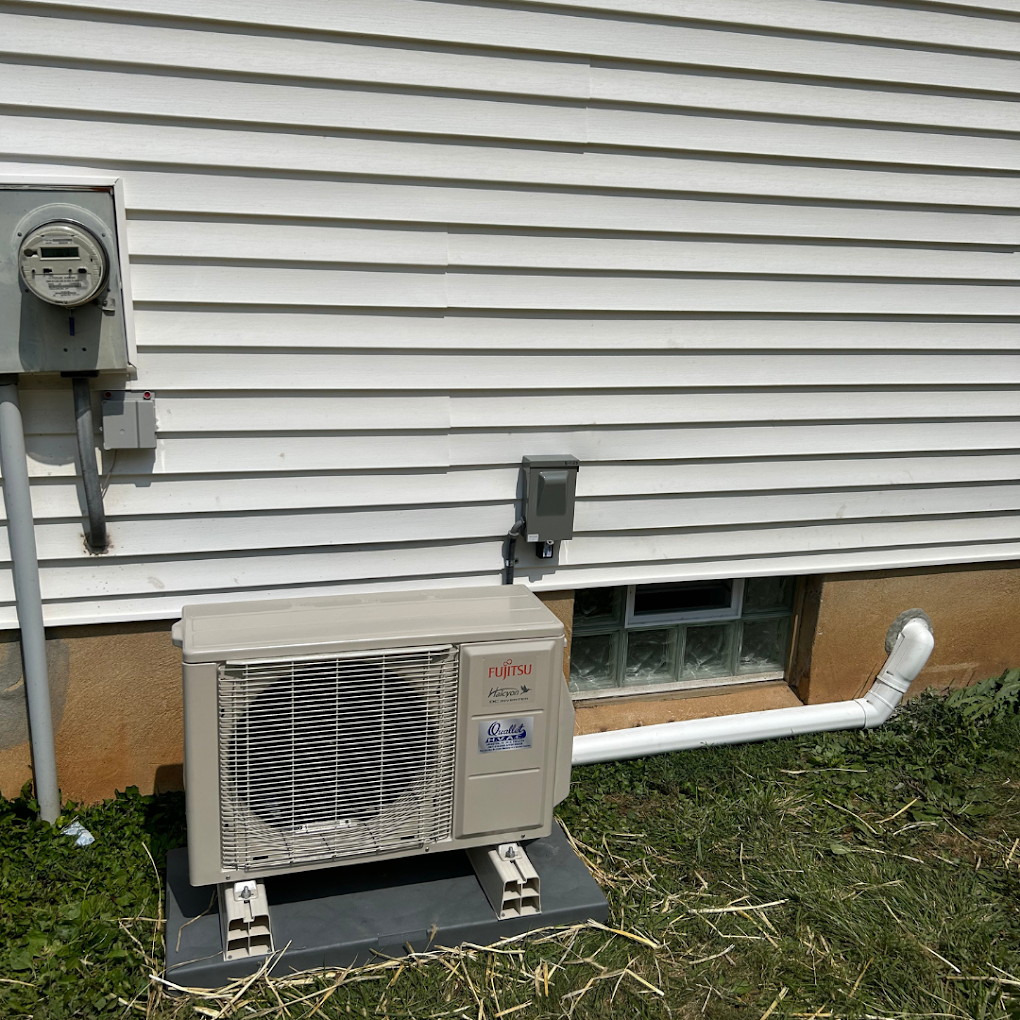 An air conditioner is sitting outside of a house next to a window.