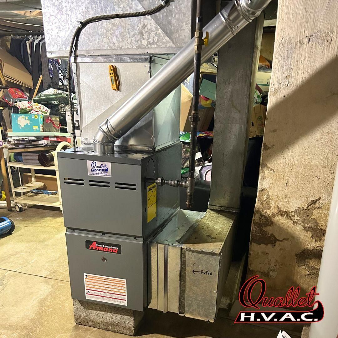 A furnace is sitting in a basement next to a wall.