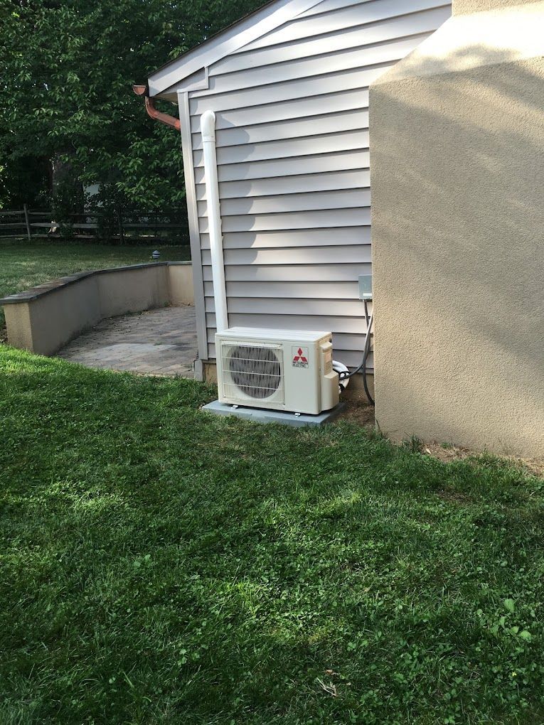 A white air conditioner is sitting on the side of a house.