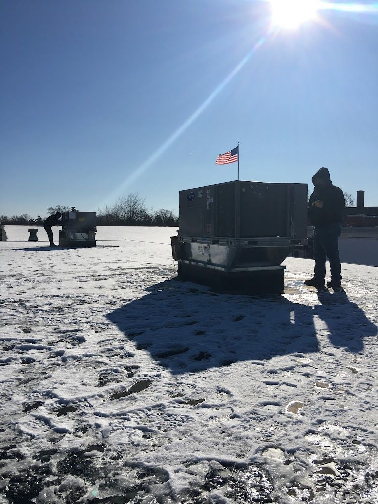 A man is standing on top of a snow covered roof.