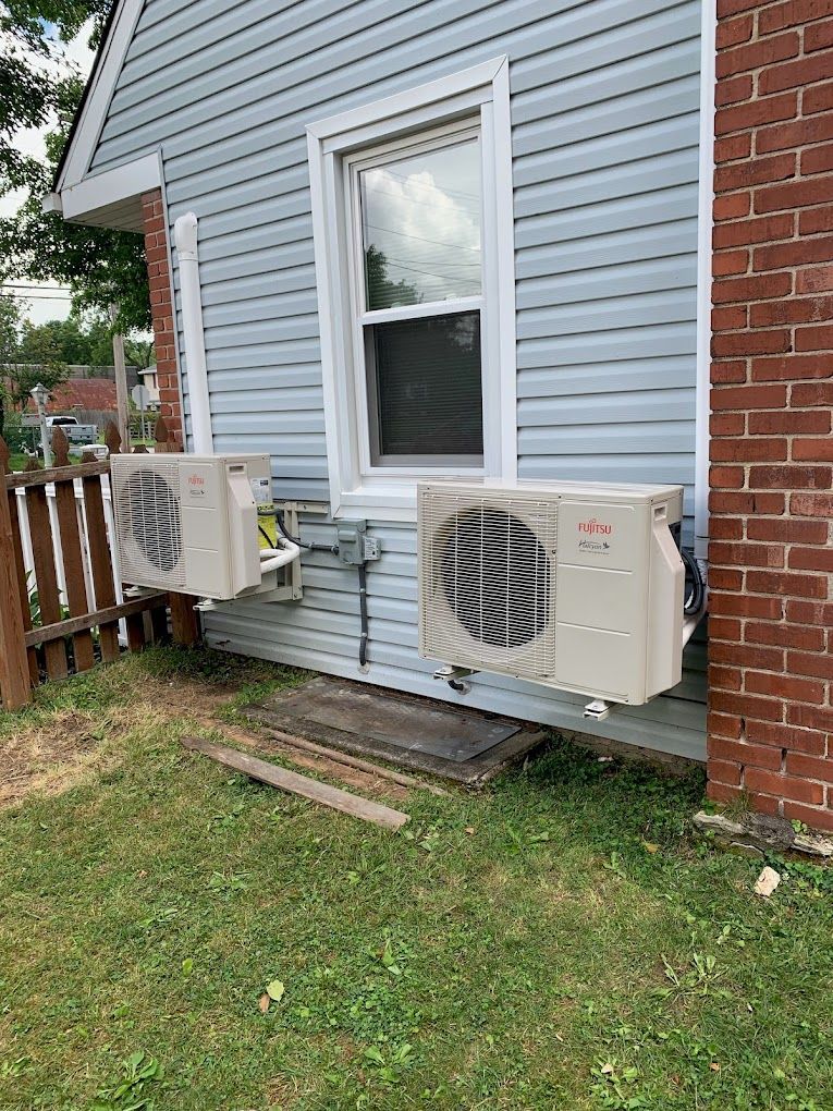 Two air conditioners are installed on the side of a house.