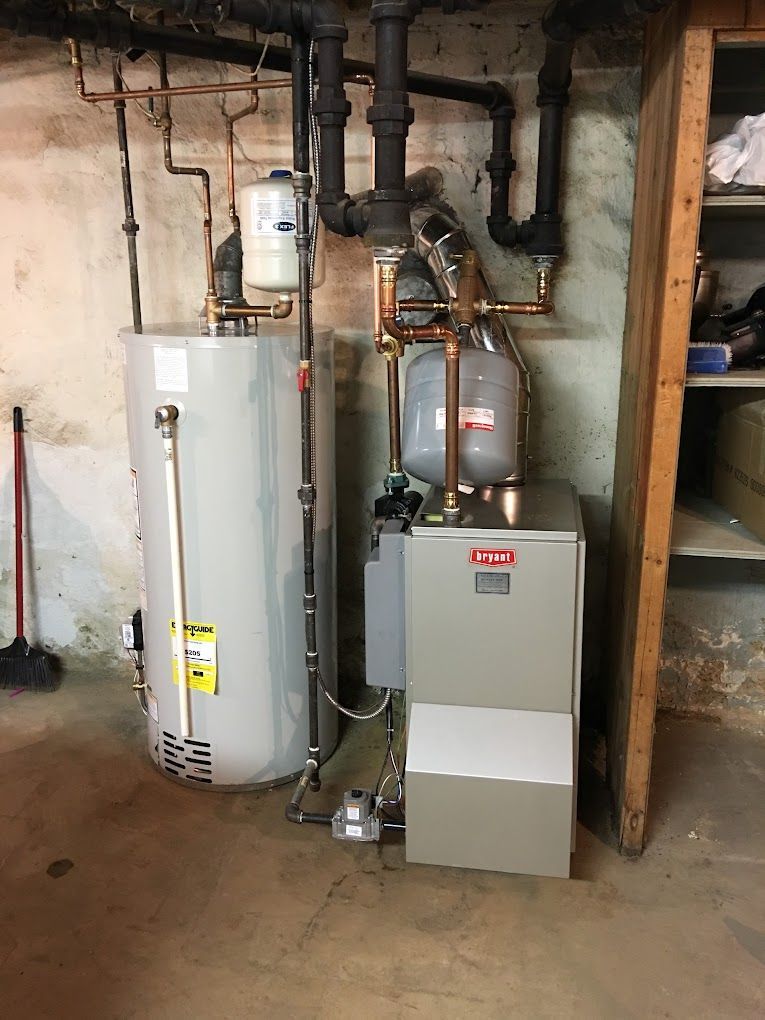 A water heater and a gas boiler are in a basement.