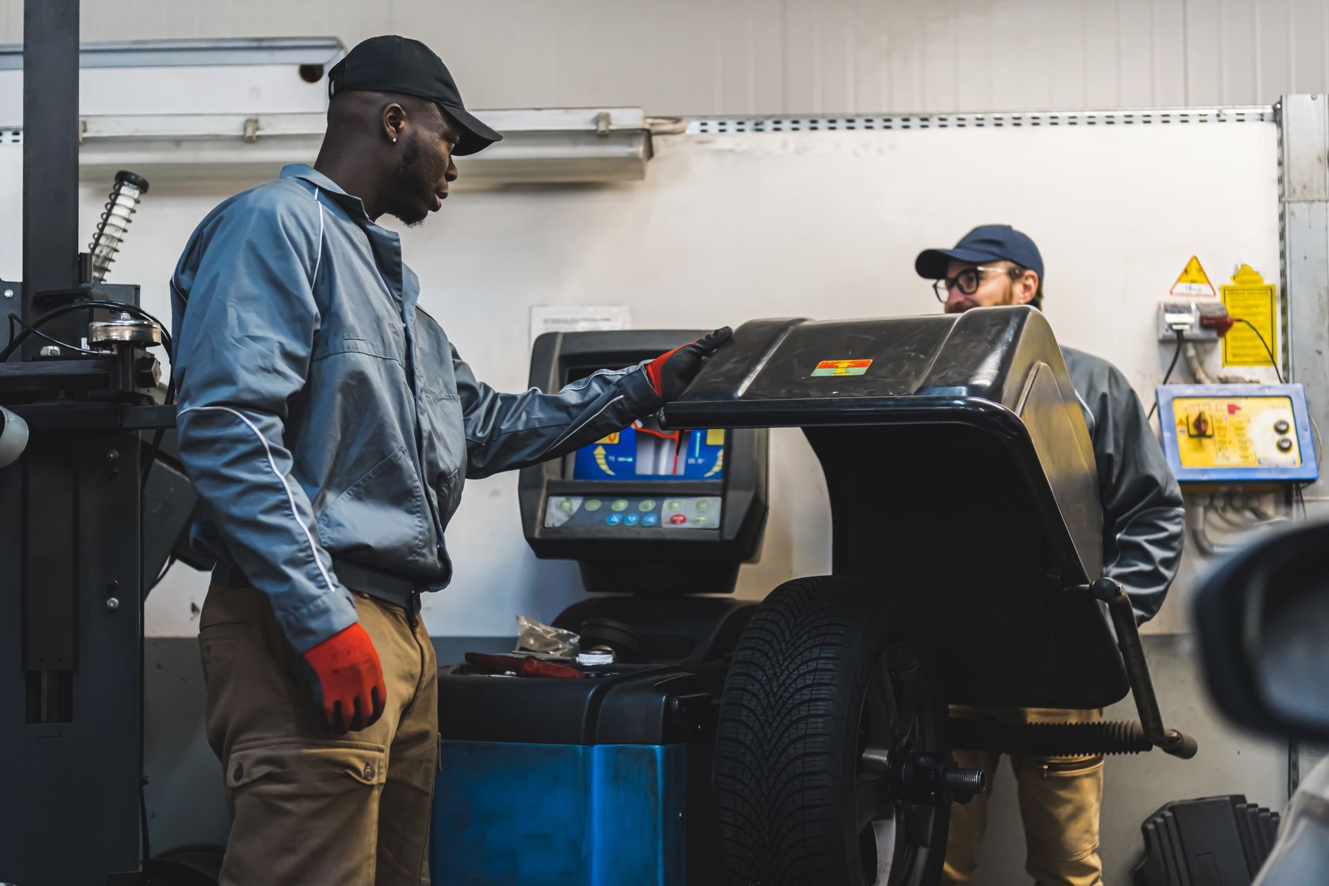 Two mechanics operating a computerized car wheel balancer | Simons Service