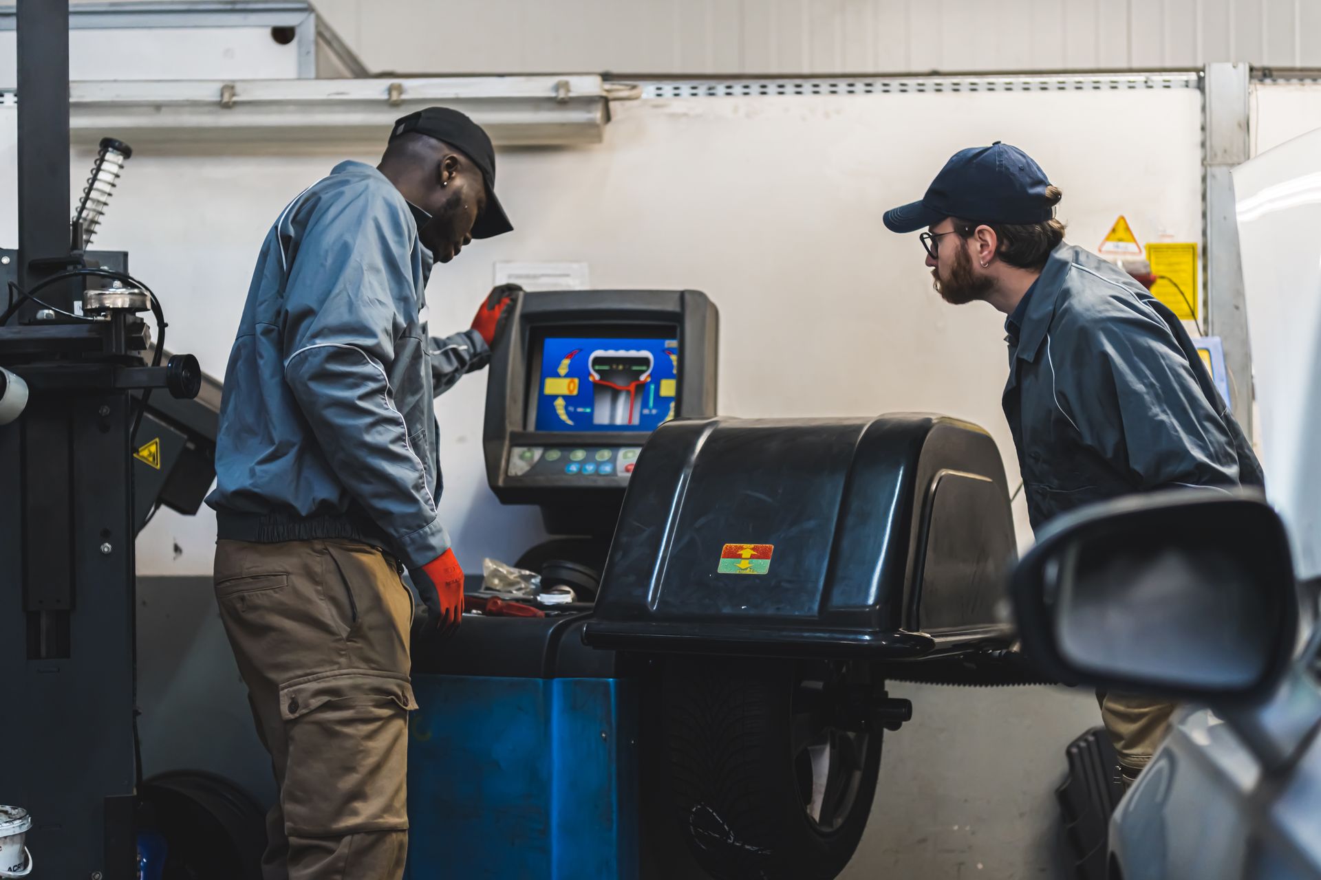 Two workers inspect a road force balancing machine in an auto repair shop | Simons Service