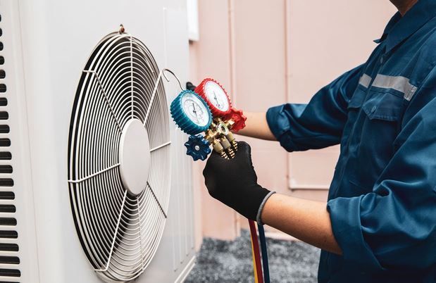 Technician performing commercial refrigeration services by checking pressure gauges on an outdoor un