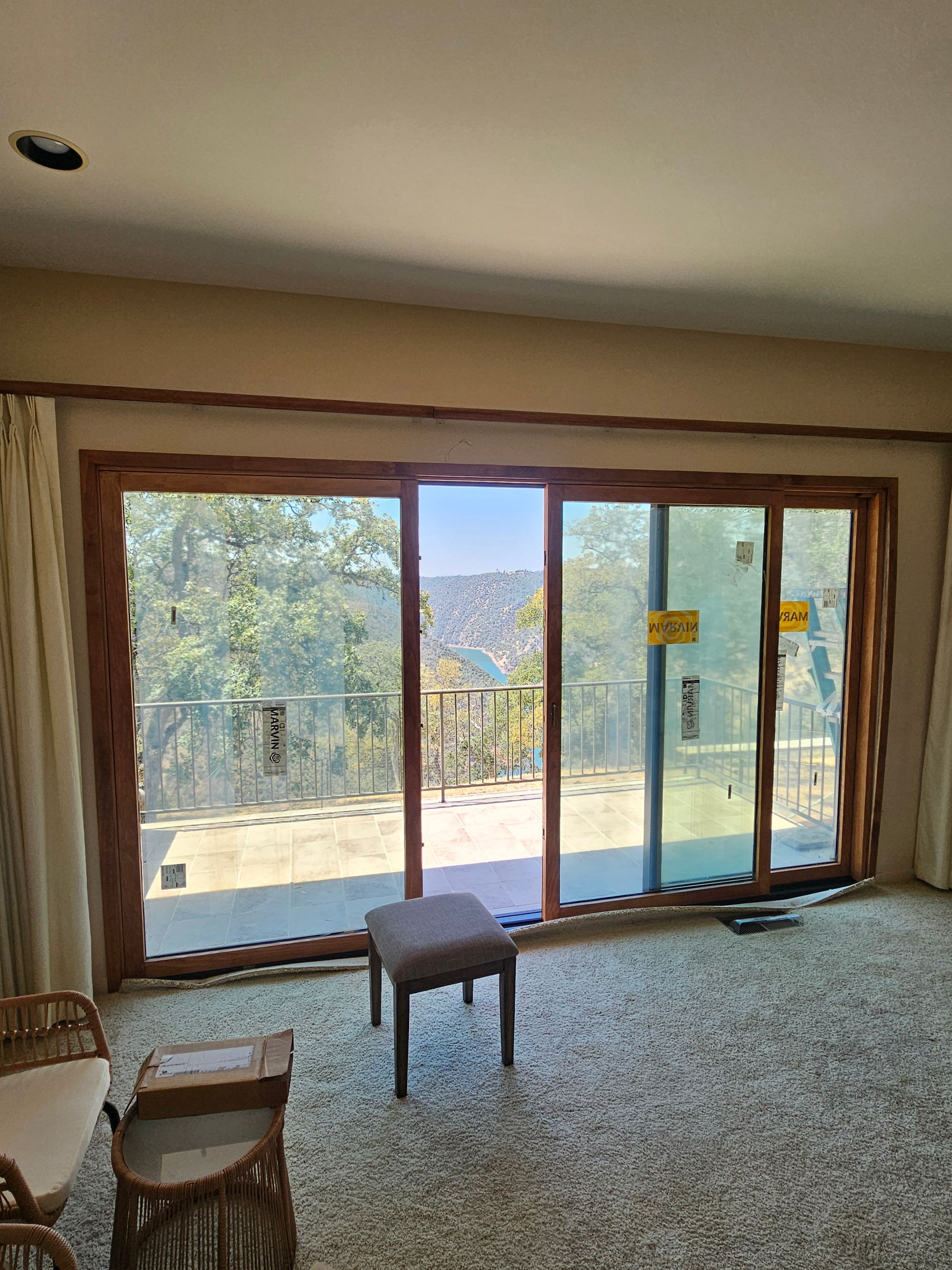 Empty living room with large sliding glass doors opening to a sunny patio and mountains beyond