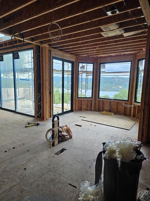 Unfinished room with exposed framing, large windows, and a lake view under construction.