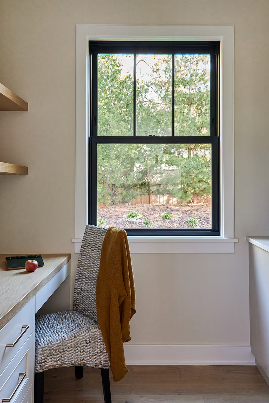 Small home office nook with a window, chair, desk, and shelves in neutral tones.