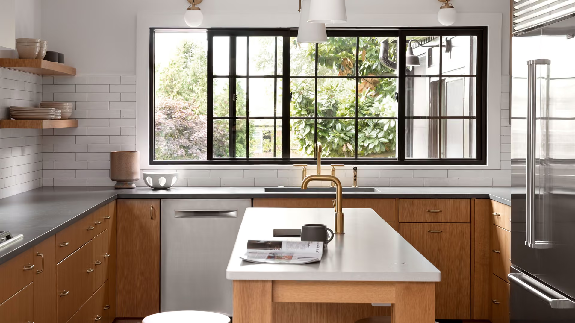 Modern kitchen with white island, wood cabinets, black-framed window, and brass faucet.