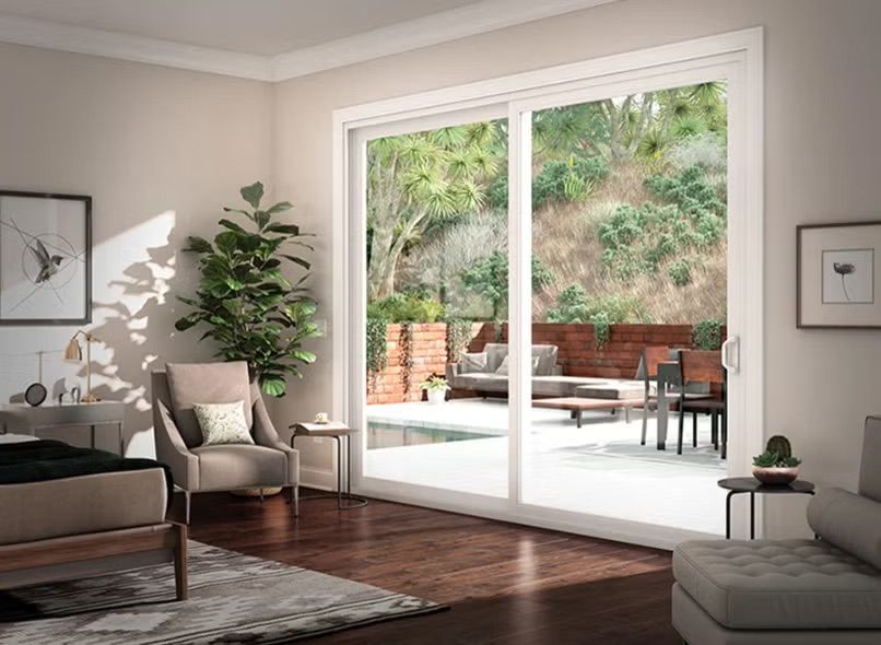 Modern living room with large glass doors opening to a patio and trees outside