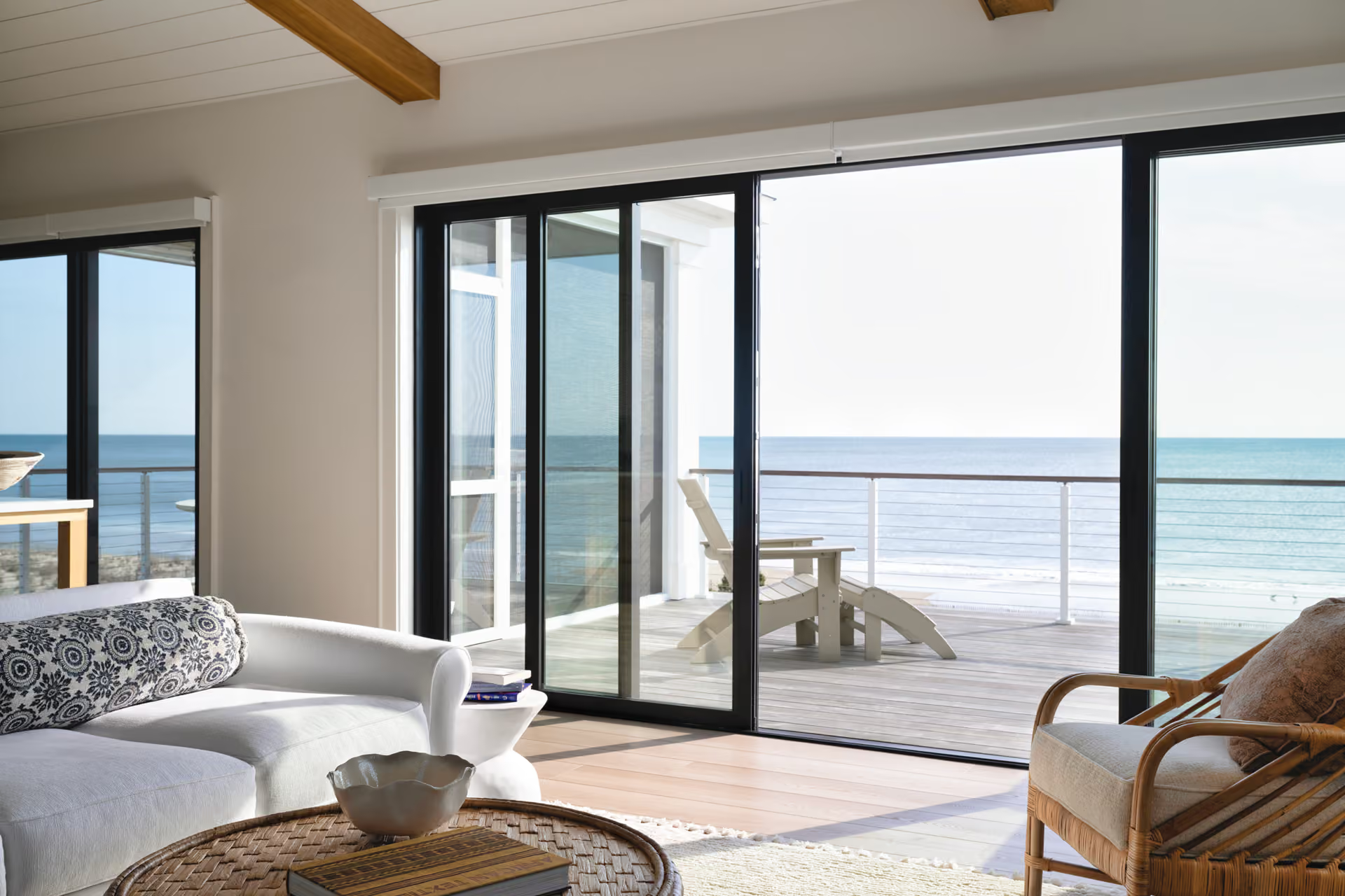 Bright living room with open glass doors to a seaside deck and ocean view