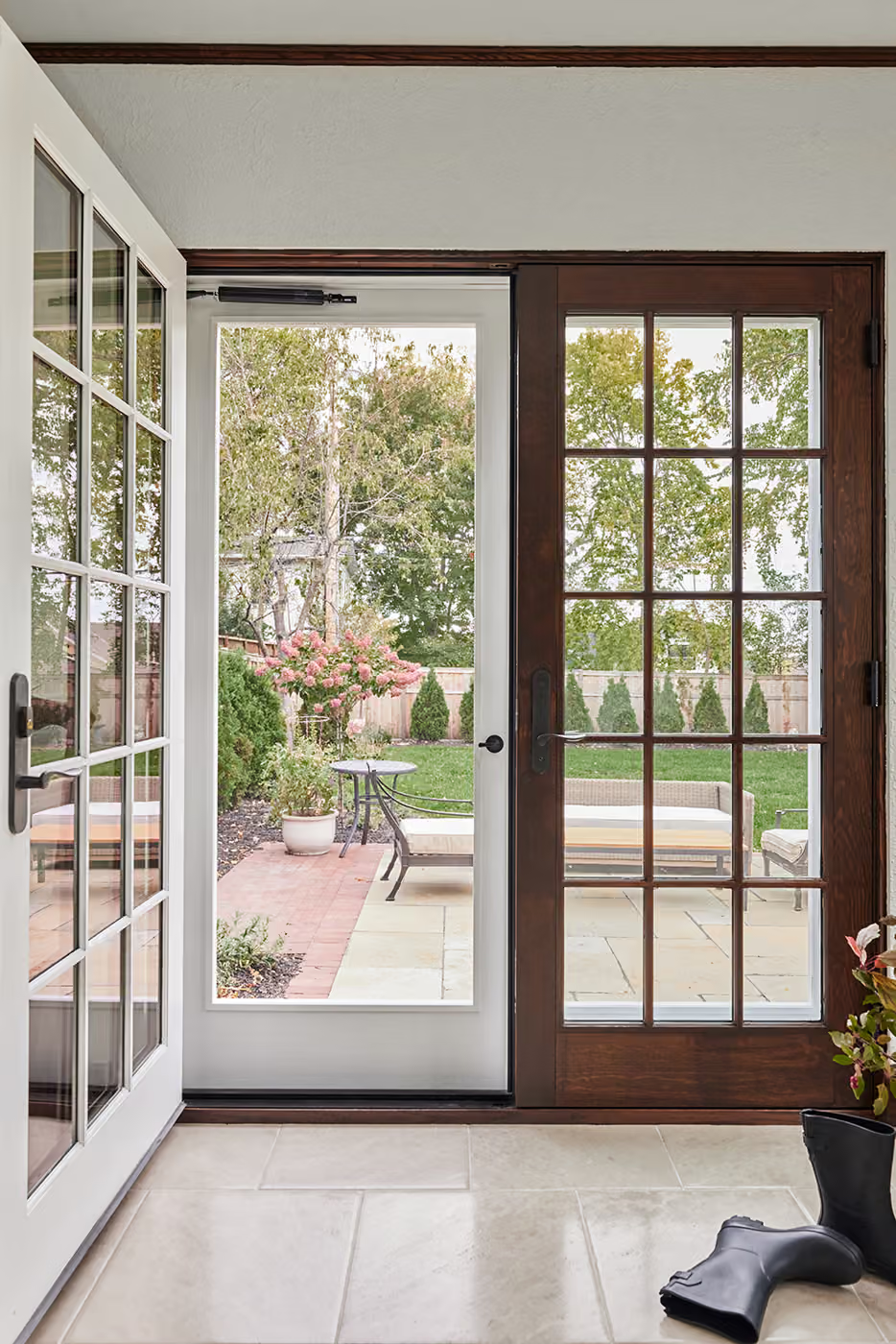 Sunlit doorway with French doors opening to a garden patio and outdoor seating