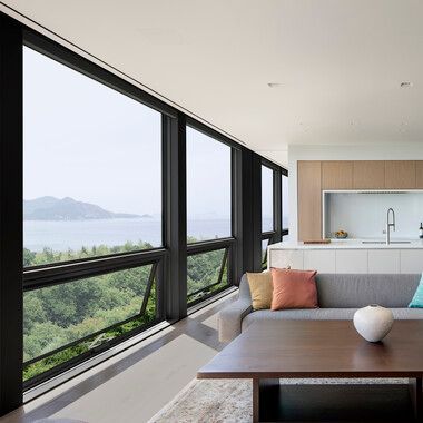 Modern living room with floor-to-ceiling windows overlooking a lake and mountains