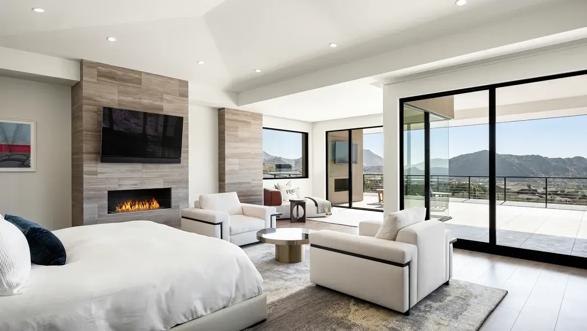 Modern living room with fireplace, white sofas, and large sliding glass doors overlooking a water view