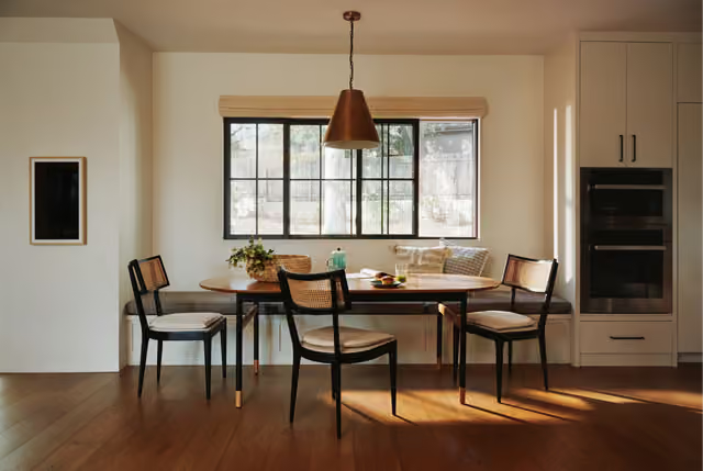 Modern dining room with a wooden table, black chairs, and a large window.