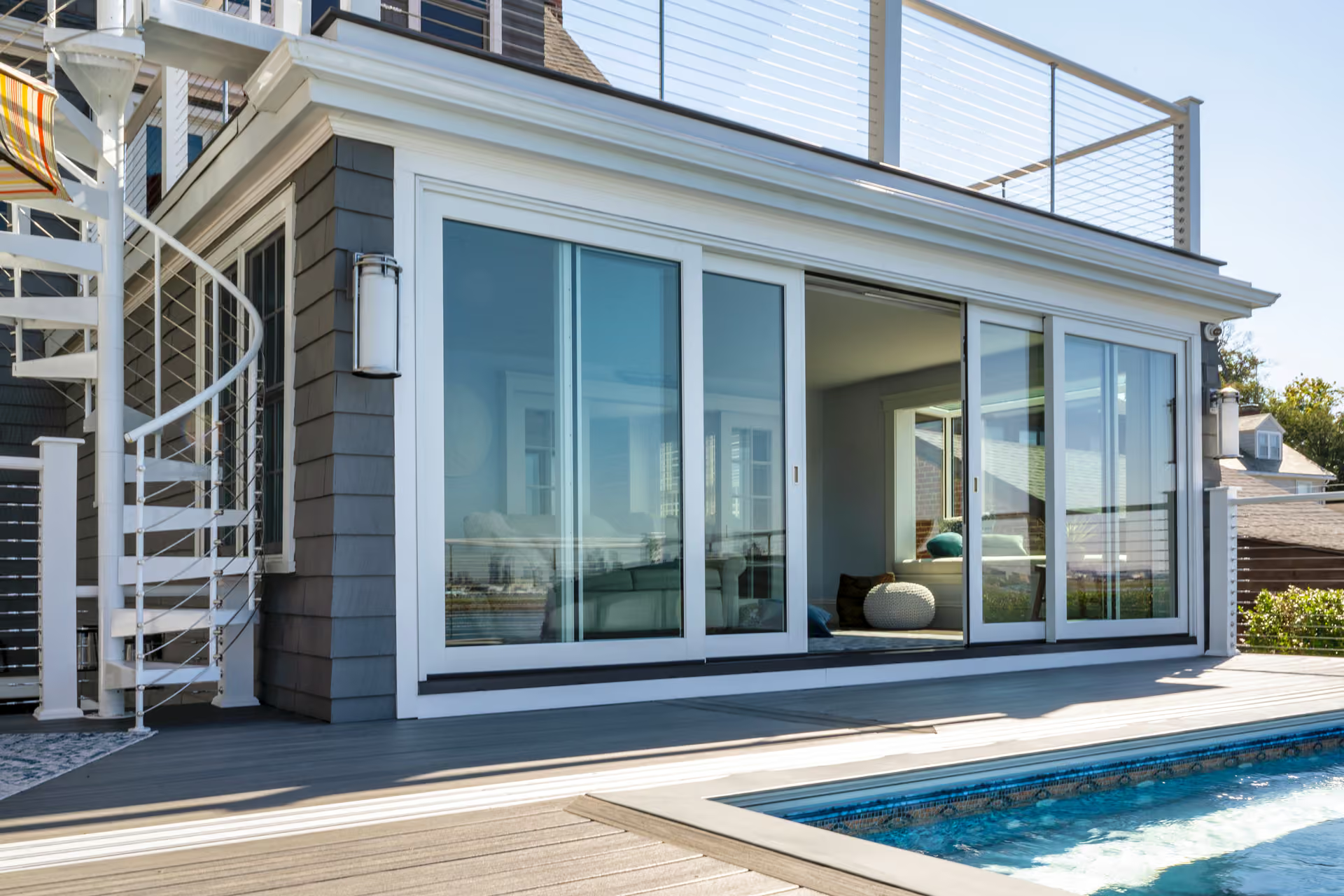 Modern house patio with large sliding glass doors beside a swimming pool