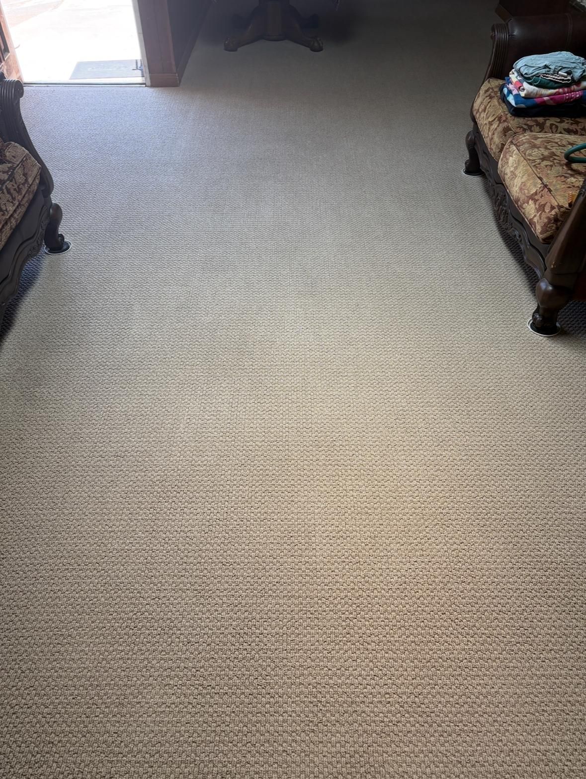 Carpeted room with two upholstered chairs by the walls and a small bag on the right chair.