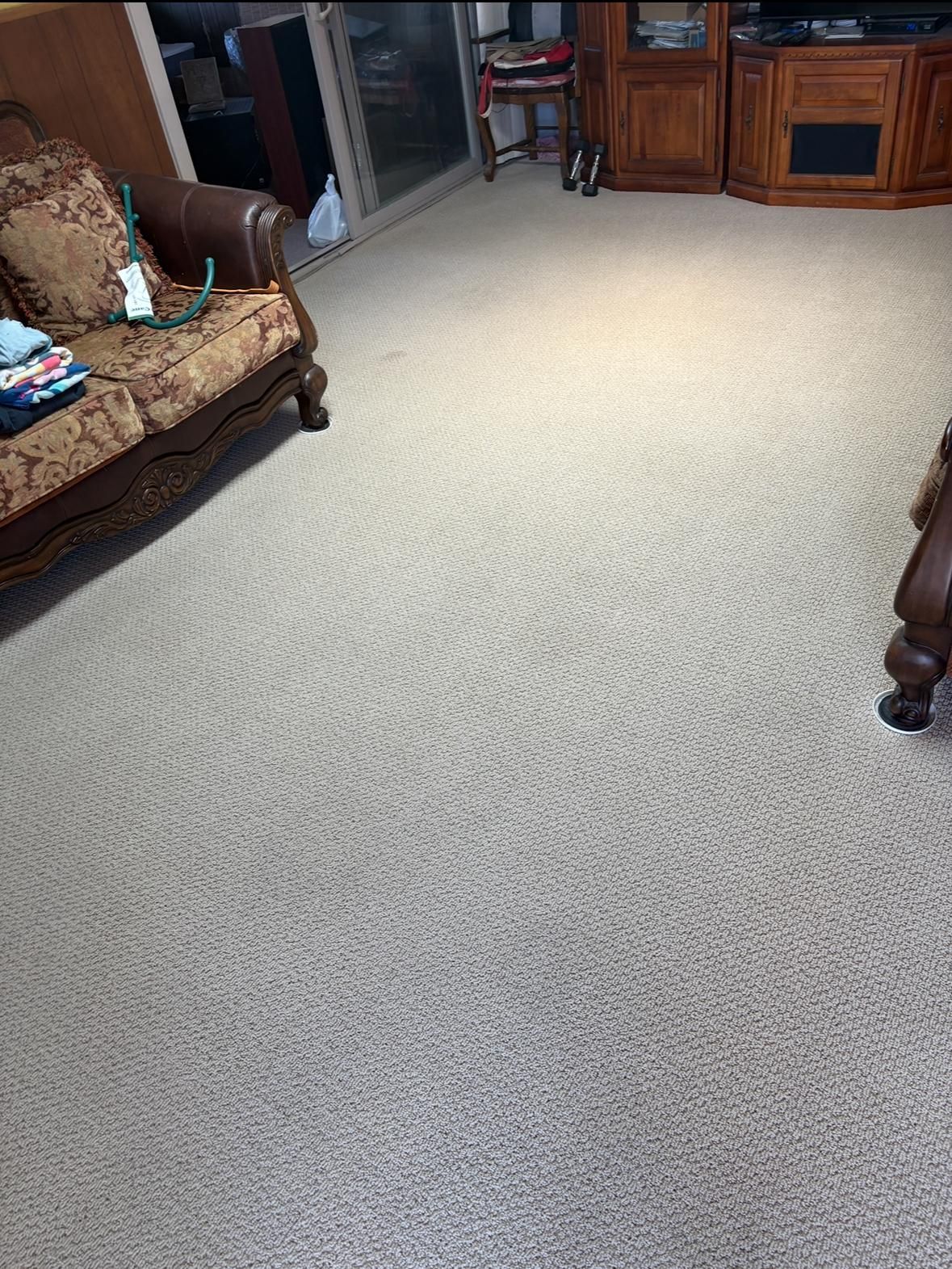 Living room with beige carpet, brown sofas, and a wooden TV cabinet in the background