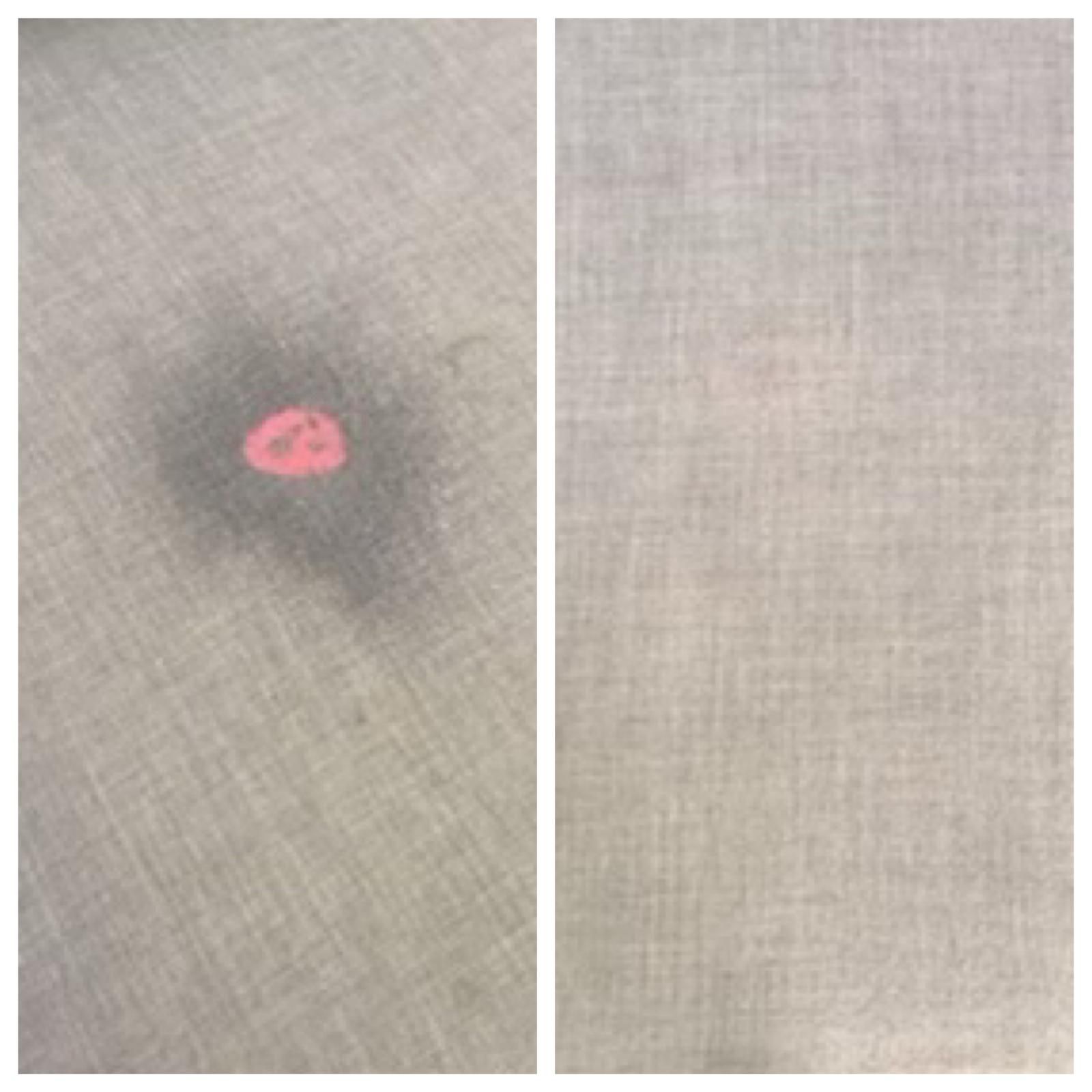 Close-up of beige fabric with a small pink stain surrounded by a dark smudge.