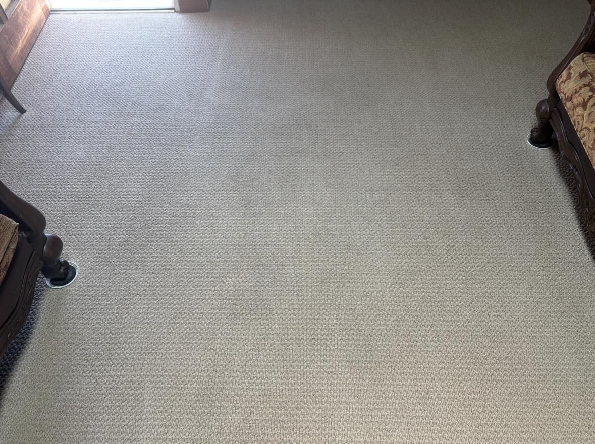 Light gray carpeted floor with sunlight near the top edge and dark furniture on the sides