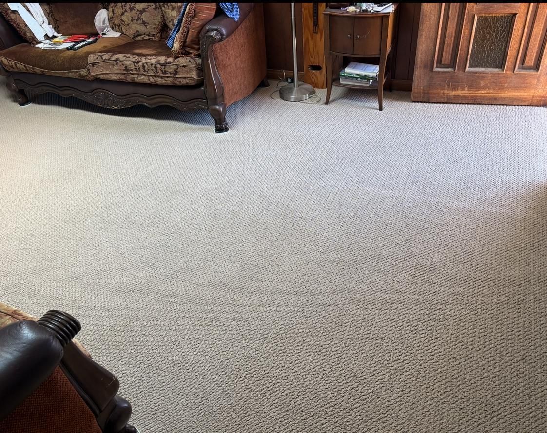 Living room with a large light beige carpet, sofa, and wooden cabinet