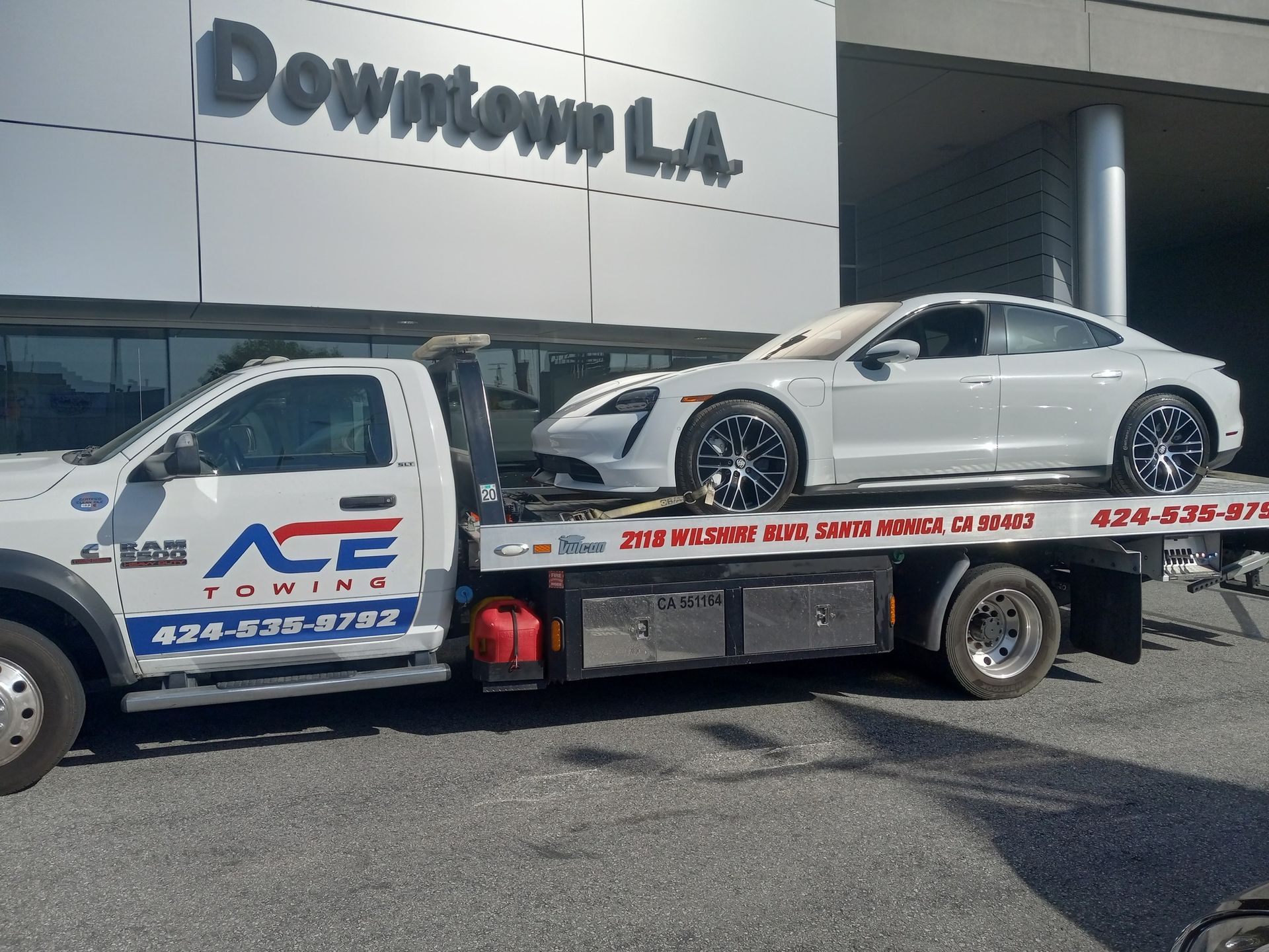 Tow truck hauling a white sports car outside Downtown L.A. building