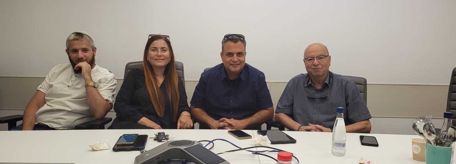 קבוצת אנשים יושבת ליד שולחן בחדר ישיבות.