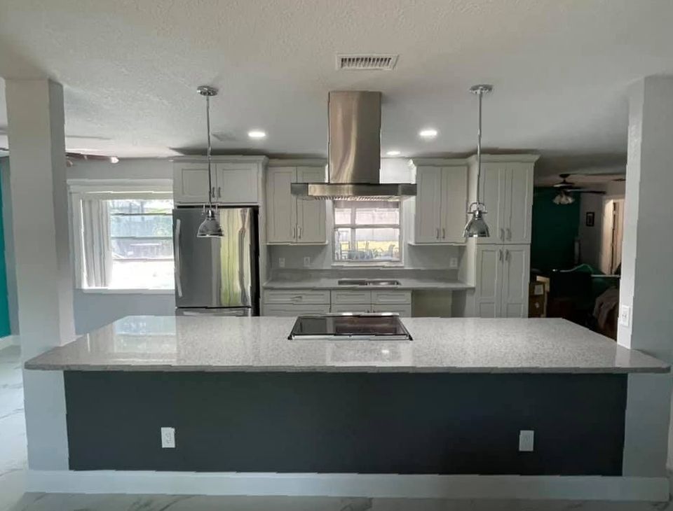 A kitchen with white cabinets , stainless steel appliances , and a large island.