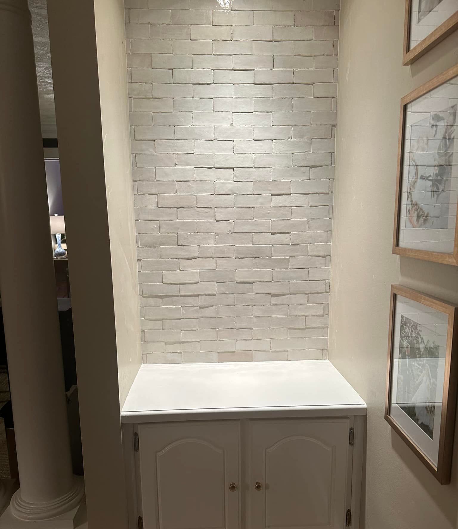 A hallway with a brick wall and a white cabinet