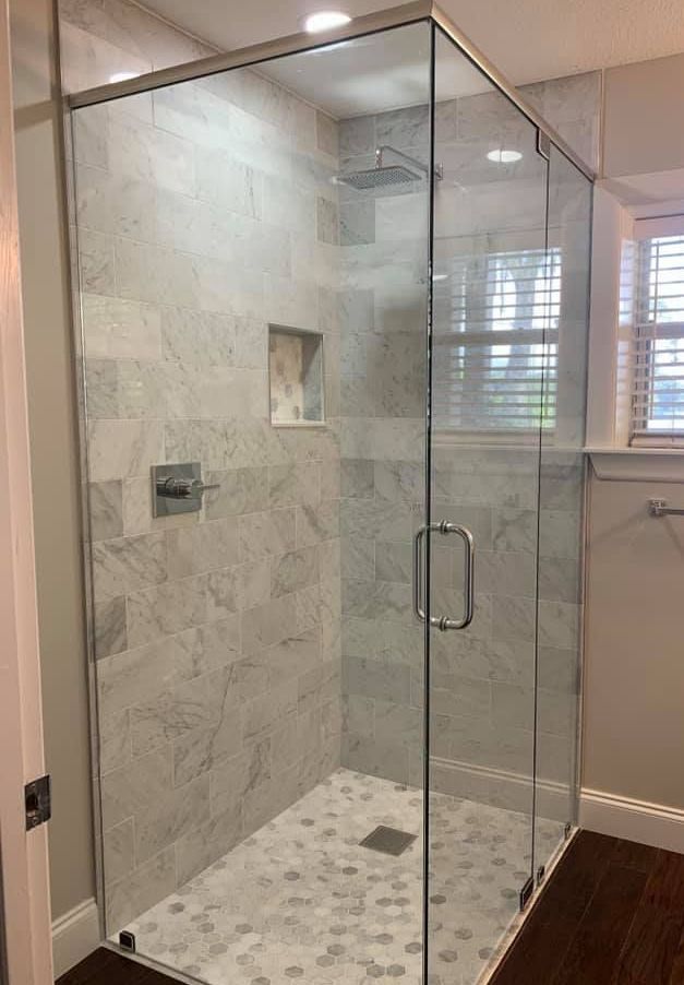 A bathroom with a walk in shower with a glass door.