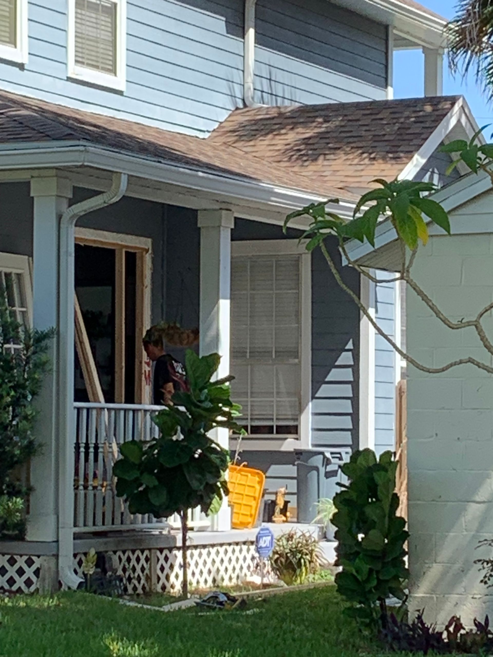 a man stands on a porch next to a sign that says adt