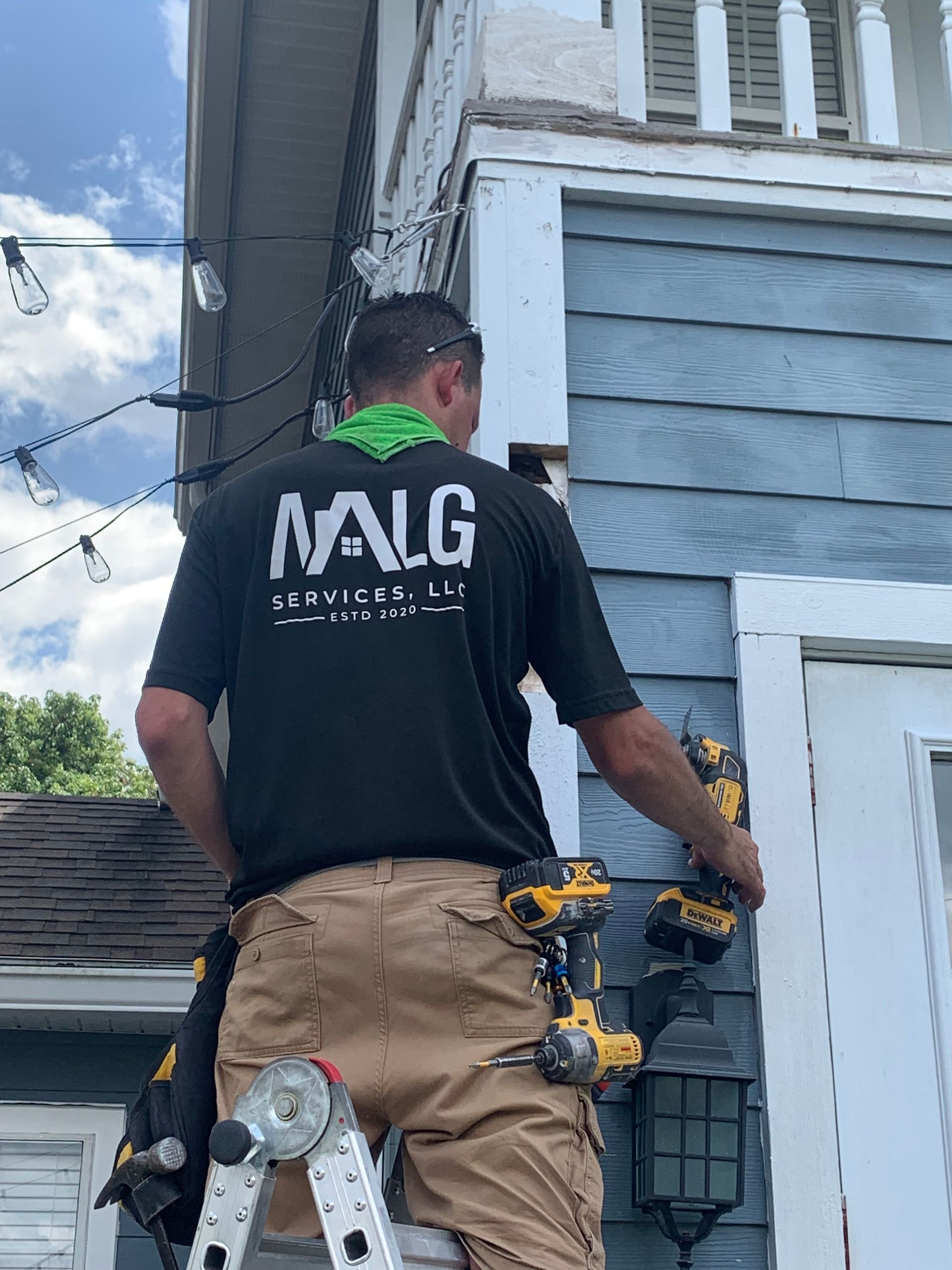 A man is standing on a ladder working on a house.