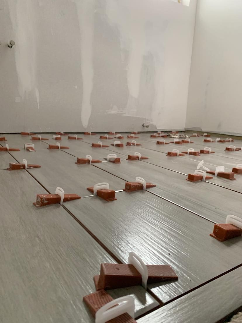 A room with a lot of tiles and spacers on the floor.