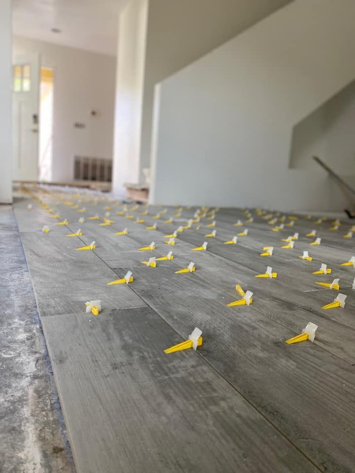 A wooden floor with yellow tile spacers on it.